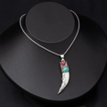 Detailed view of wolf tooth pendant with silver relief, red gemstone, and turquoise inlay - White Animal Tooth with Red and Blue Turquoise