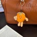 Handmade orange wool felt keychain with cute expression hanging on a stylish brown leather bag - Orange Persimmon