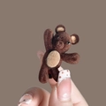 Detailed close-up of a brown flocked bear hair clip held by hand against a brown background - Bear