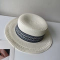 Détail d'un chapeau de paille à toit plat avec ruban ethnique tissé bleu et noir élégant - crème