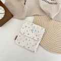Detailed close-up of a blue floral fabric pouch with button closure and brand label - Large White
