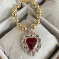 Detailed shot of retro gold beads and red enamel heart pendant in a jewelry tray - Baroque Textured Red Heart Style (6)