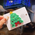 Gros plan sur une barrette de Noël en tricot vert avec broderies faite à la main - Sapin avec Nœud en Tissu Éponge