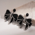 Close-up of black bow earrings with rhinestones on a beige shell background - Rhinestone Bowknot Style / Silver Earring Post-Black