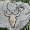 Macro view of Western bull head keychain with leopard fur texture on stone background - Brown White Spotted Bull Head