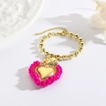 Detailansicht eines goldenen Perlenarmbands mit einem rosa verzierten Herzanhänger - Rosa