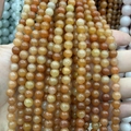 Strang mit runden orangebraunen Natursteinperlen für DIY-Schmuck in der Hand gehalten - Hongdongling A735 / 4mm (ca. 88 Perlen)