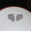 Macro shot of sparkling crystal leaf earrings on a white ceramic plate tray - One Size / Silver Earring Post Rhinestone Firework Flower Stud Earrings