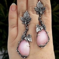 Vintage silver vine leaf earrings with teardrop pink stones held by hand in natural light - Blue