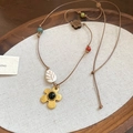 Vue détaillée du collier ethnique avec fleur dorée et pendentif feuille en céramique - Collier-Brun-Or-Fleur
