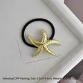 Macro detail of golden starfish hair tie with embossed dots on a white textured tray - Gold Dotted Starfish