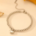 Poliertes Edelstahl-Perlenarmband mit 3D-Herzanhänger auf texturiertem Hintergrund - Stahlfarbenes Herz-Armband mit glatten Perlen (Karabinerverschluss)