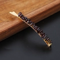 Macro shot of gold hair clip with natural reddish-brown garnet stone beads on wood - Garnet Gold