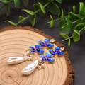Primer plano detallado de pendientes de flores de esmalte azul con perlas barrocas naturales grandes. - Pendientes de Flor Barroca