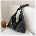 Detalle de un bolso tote de cuero suave negro en superficie blanca minimalista - Negro