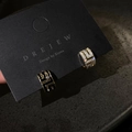 Detailopname van geometrische oorbellen met zwart email en sprankelende witte zirkoon - Goud (Zilveren oorsteker)