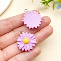 Close-up of purple resin daisy flower pendants with yellow centers for DIY jewelry making - Purple
