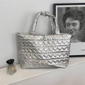 Detail der silbernen gesteppten Herz-Tragetasche mit Markenlabel auf weißem Tisch - Herz Muster Silber Mittel / Silber