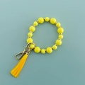 Gros plan sur la dragonne en perles jaunes avec pompon assorti et fermoir en métal doré - Jaune