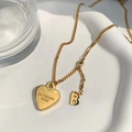 Golden heart pendant necklace with Cuban chain on a minimalist white ceramic tray - Letter Heart Pendant Style (8923) / Gold