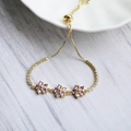 Dettaglio bracciale floreale dorato regolabile con zirconi viola e chiusura a scorrimento - Viola