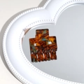 Macro detail of amber tortoiseshell claw clip on a white heart mirror setting - Amber