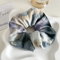 Macro shot of large tie-dye fabric scrunchie with abstract blue and beige patterns - Pleated Tie-dye / Blue