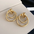 Dettaglio degli orecchini geometrici dorati con tre cerchi in metallo intrecciati - Oro