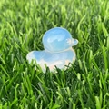 Single milky white translucent crystal duck figurine placed on green artificial grass - Opal
