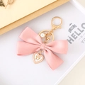 Detalle de llavero con lazo de satén rosa con colgante de corazón blanco y perla fina - Rosa