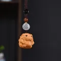 Makroaufnahme eines handgeschnitzten Thuja-Holz-Fabeltier-Anhängers mit Segensperle - Pixiu Segen Schlüsselanhänger