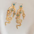 Boucles d'oreilles serpent dorées vintage avec perles bleues et motifs soleil et lune - Doré