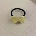 Elastic hair tie featuring a geometric gold metal piece with irregular textured finish - Curved Oval Crocodile Pattern Gold