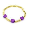 Close-up of golden beaded bracelet featuring three vibrant purple enamel heart charms - Purple