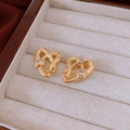 Dettaglio di orecchini a cuore a serpente dorati con zircone su velluto beige - Placcato Oro Vero Oro