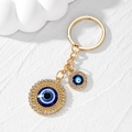 Close-up of golden Evil Eye keychain with intricate cut-outs and sparkling white crystals - Gold Large Round Eye