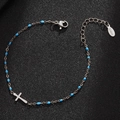 Detail showing silver stainless steel cross bracelet with blue beads on black surface - Silver-Lake Blue