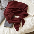 Dettaglio sciarpa in maglia bordeaux con etichetta su cappotto grigio e lenzuola a quadri - Rosso