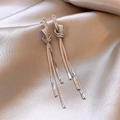 Detail view of silver tassel earrings with crystal knot on champagne silk fabric - Silver Knotted Zircon Tassel