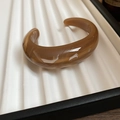 Detail of amber acrylic bangle showing marble texture on a white striped tray - Dark Coffee Marble