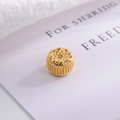 Macro shot of S925 sterling silver hollow cylinder charm with vintage gold floral pattern - Hollow Patterned Bead Style
