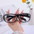Glossy black full-frame cycling goggles with side protection held in hand - Black Frame Clear Lenses