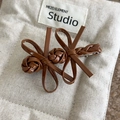 Detail of dark brown leather bow hair clip with vintage braided texture and silver metal grip - Brown Coffee