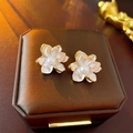 Elegant gold-edged white flower stud earrings featuring pearls on a jewelry box - White Pearl Flower