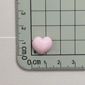 Close-up of a 1.5cm glossy pink resin heart charm shown on a scale for size reference - Pink