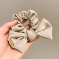 Detail of beige bow scrunchie with cute bear patch and Baby Happy Made label - Off White