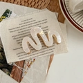 Close-up of wave-shaped pearlescent hair claw clip on vintage lyric paper background - M-Shape Style