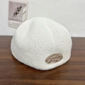 Detalle de gorro de punto blanco con placa de metal cepillado de alta calidad en primer plano - Blanco