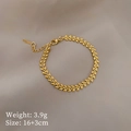 Dettaglio del bracciale dorato con trama a foglia e catena regolabile su tessuto grigio - S509 Stile Grano / Oro
