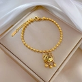 Detalle de pulsera de cuentas doradas con dije de candado FU sobre seda - P115 Dorado (P115 Dorado) / Dorado